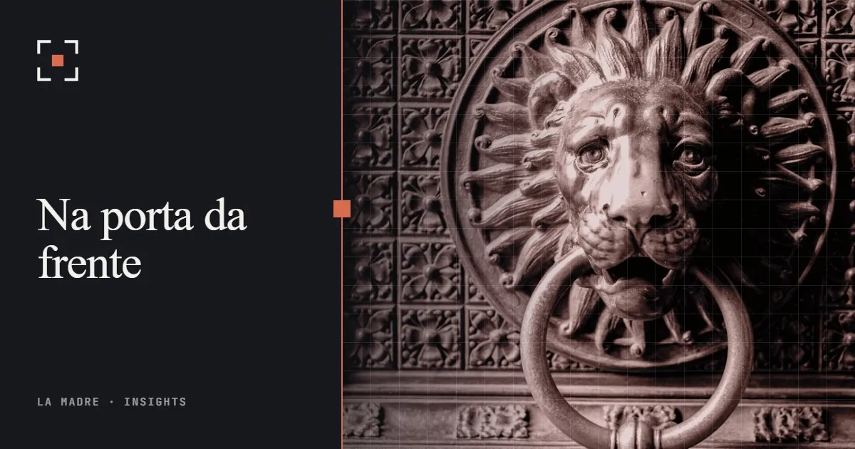 Uma aldrava de leão em latão numa porta ornamentada, no duotone da La Madre, ao lado das palavras Na porta da frente