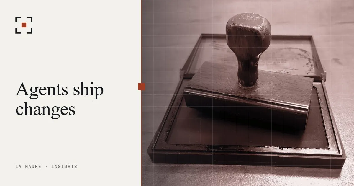 A wooden rubber stamp resting on an ink pad, in La Madre duotone, beside the words Agents ship changes
