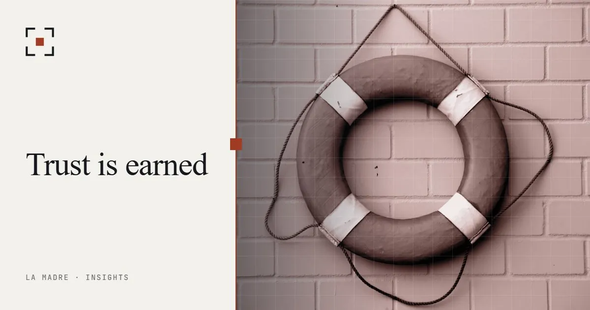 A lifebuoy hanging on a brick wall, in La Madre duotone, beside the words Trust is earned