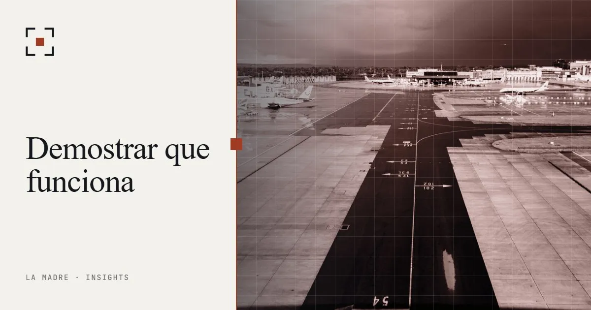 Una calle de rodaje de aeropuerto con líneas guía pintadas que llevan hacia la pista bajo un cielo oscuro, en duotono La Madre, junto a las palabras Demostrar que funciona