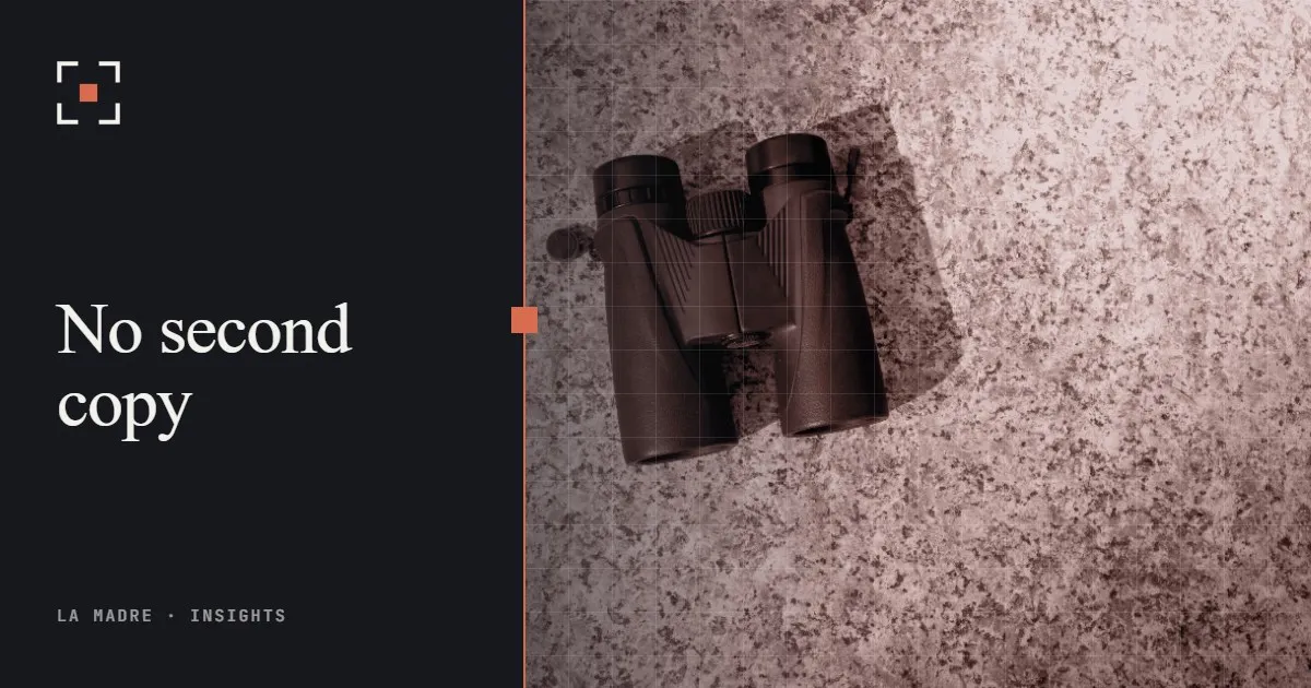 A pair of binoculars on granite, in La Madre duotone, beside the words No second copy