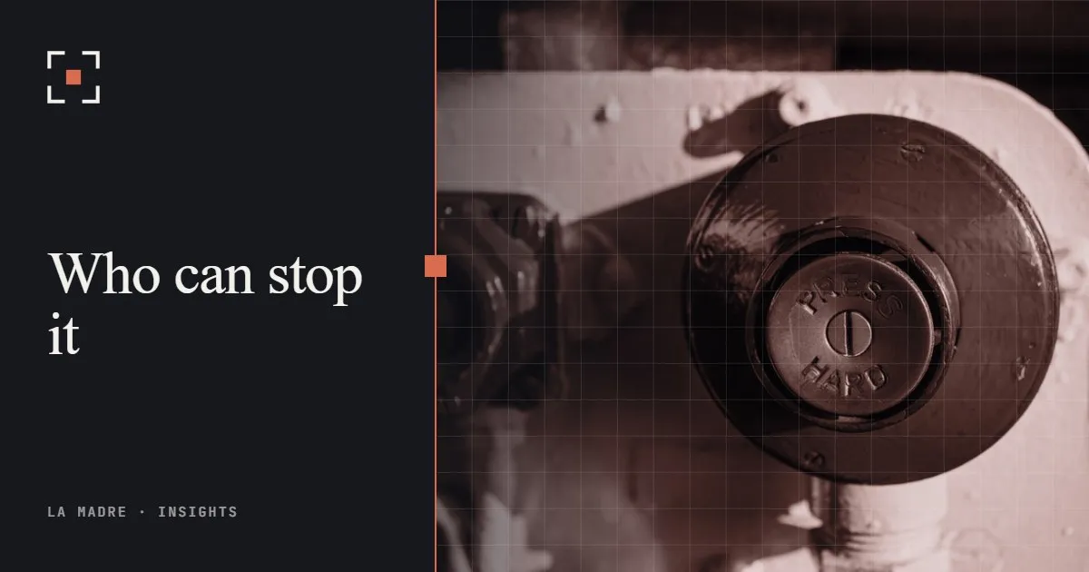 A large red emergency stop button on a machine, in La Madre duotone, beside the words Who can stop it