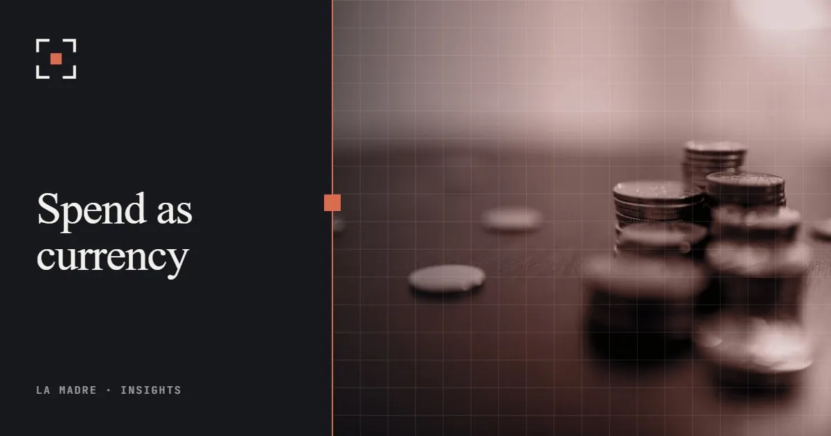 Stacks of coins on a dark wooden table, in La Madre duotone, beside the words Spend as currency