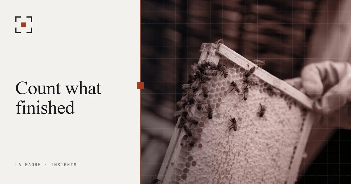 A gloved hand lifting a honeycomb frame covered with bees, in La Madre duotone, beside the words Count what finished