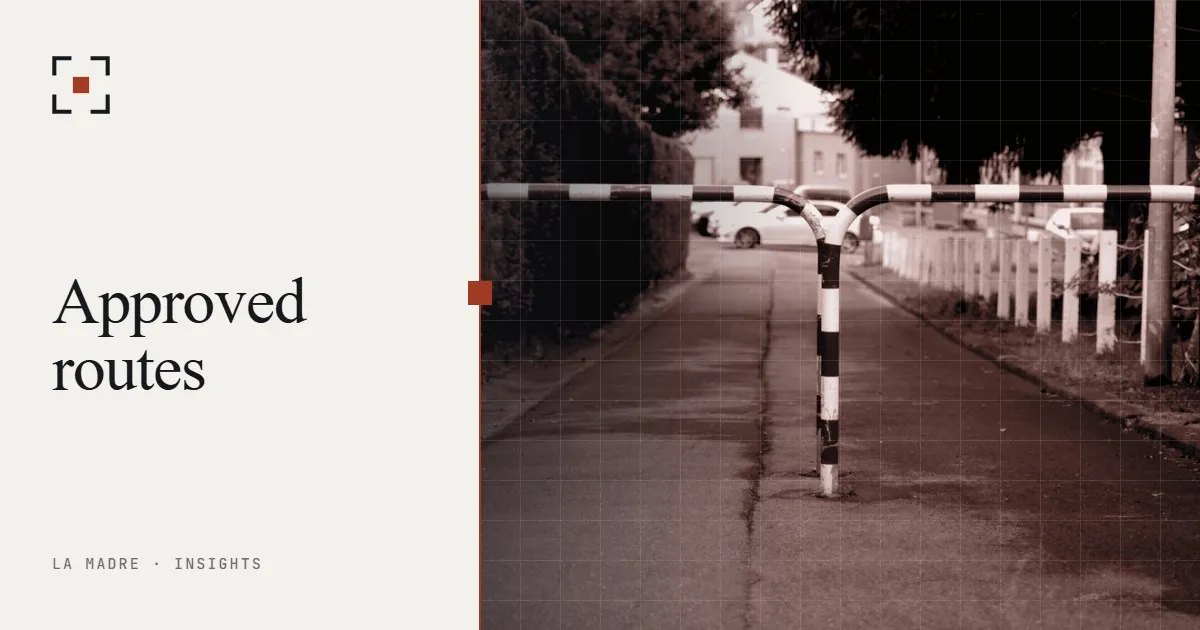 A red and white barrier across a paved path, in La Madre duotone, beside the words Approved routes