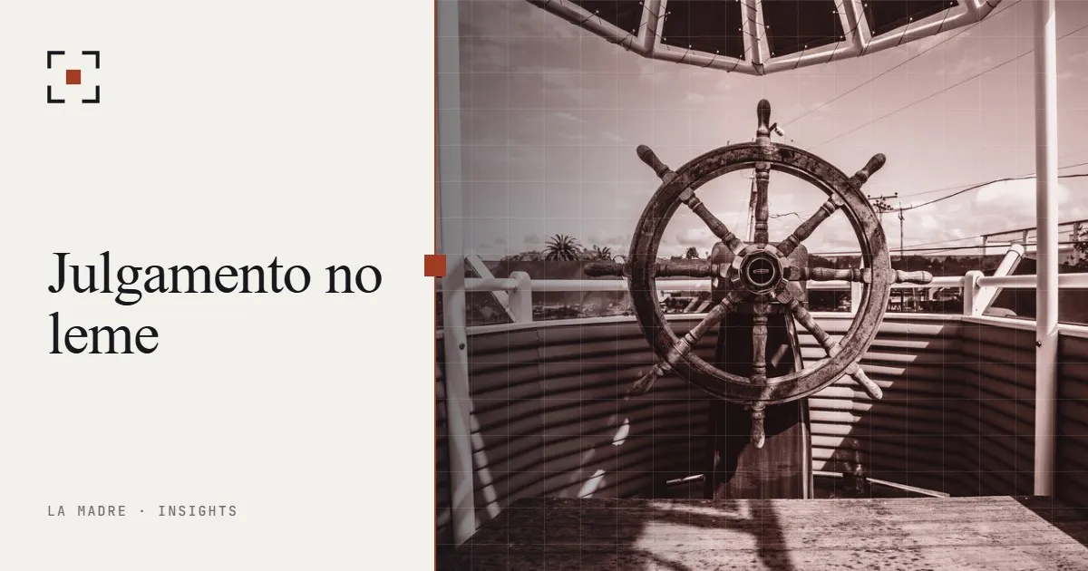 O timão de madeira de um barco voltado para o mar aberto, em duotone La Madre, ao lado das palavras Julgamento no leme