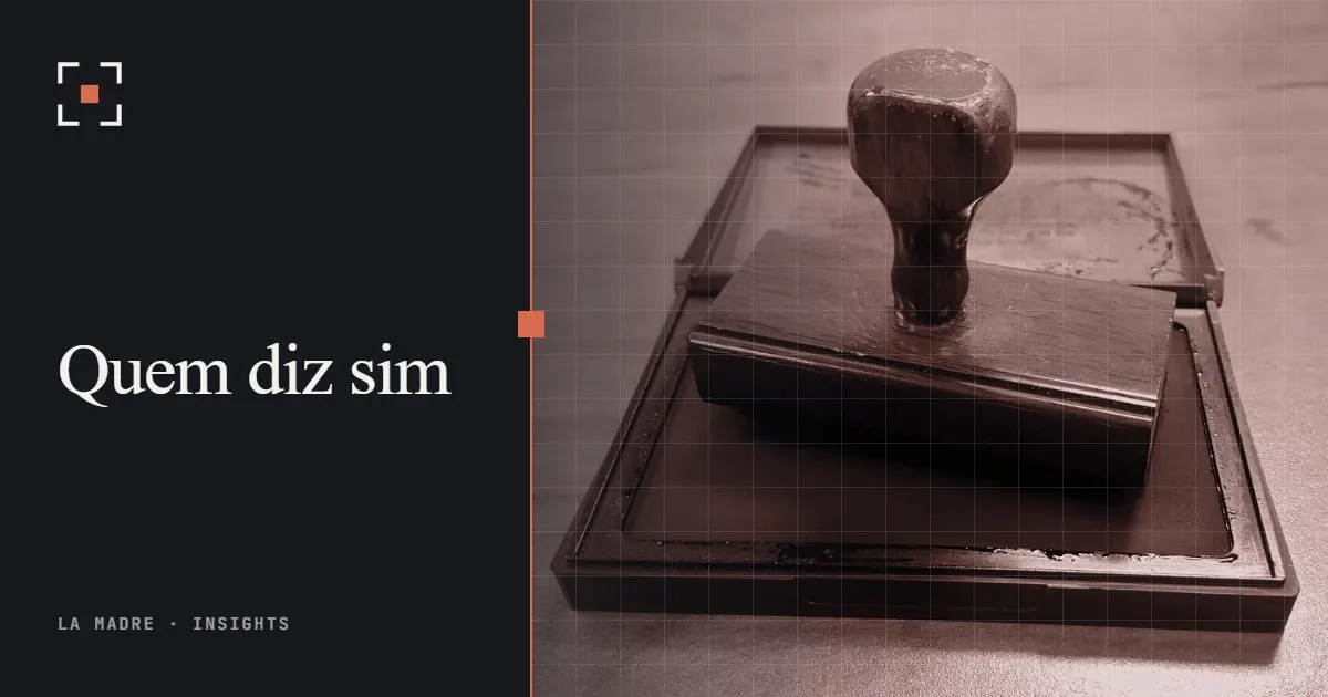 Um carimbo de madeira apoiado na almofada de tinta, em duotone La Madre, ao lado das palavras Quem diz sim