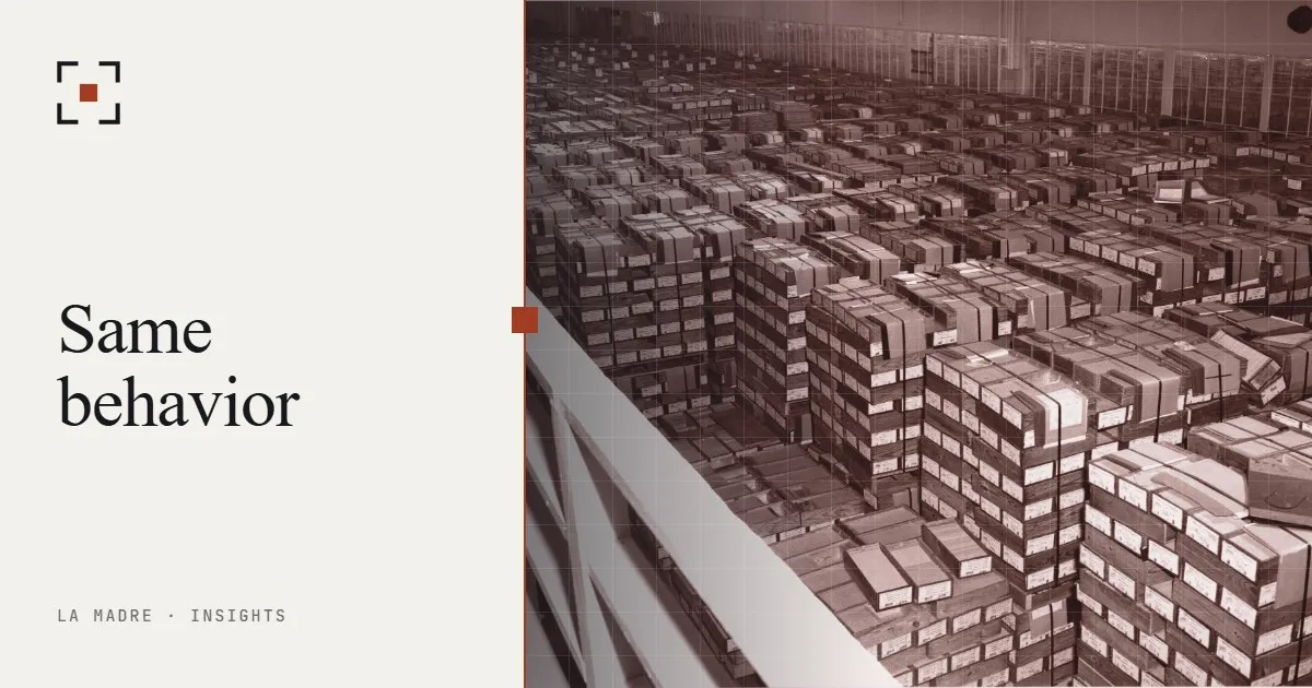 Rows of stacked IBM punch card boxes in a vast storage hall, in La Madre duotone, beside the words Same behavior